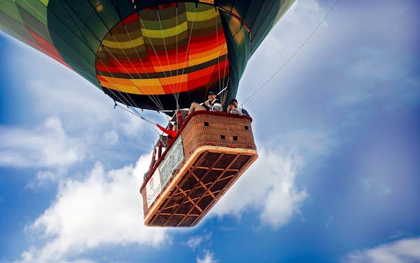 Hot air balloon with passengers in Dubai sky.