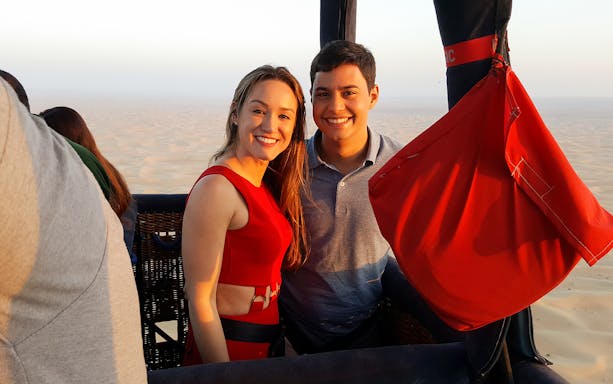 Couple enjoying a hot air balloon ride over Dubai desert.