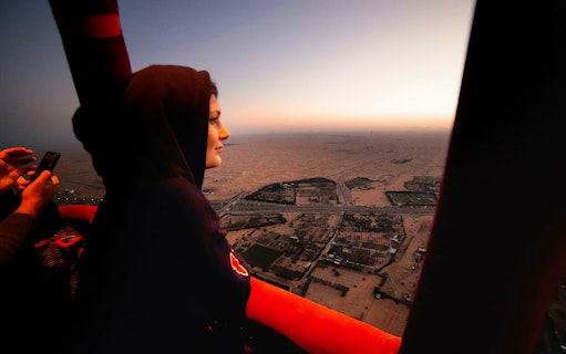 Hot air balloon view over Dubai desert at sunrise.
