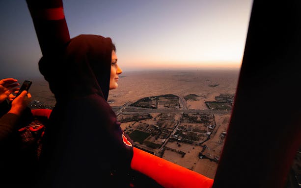 Hot air balloon view over Dubai desert at sunrise.