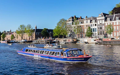 Amsterdam canal cruise boat passing historic buildings near Rembrandt House Museum.