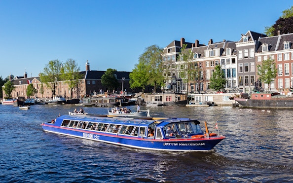 Amsterdam canal cruise boat passing historic buildings near Rembrandt House Museum.
