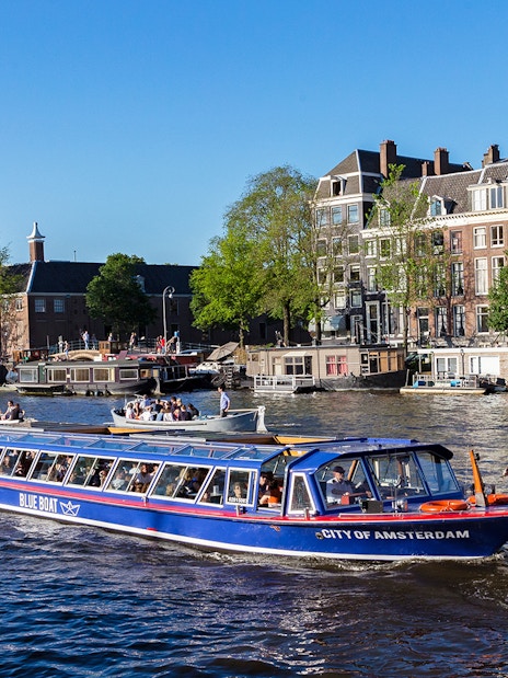 Amsterdam canal cruise boat passing historic buildings near Rembrandt House Museum.