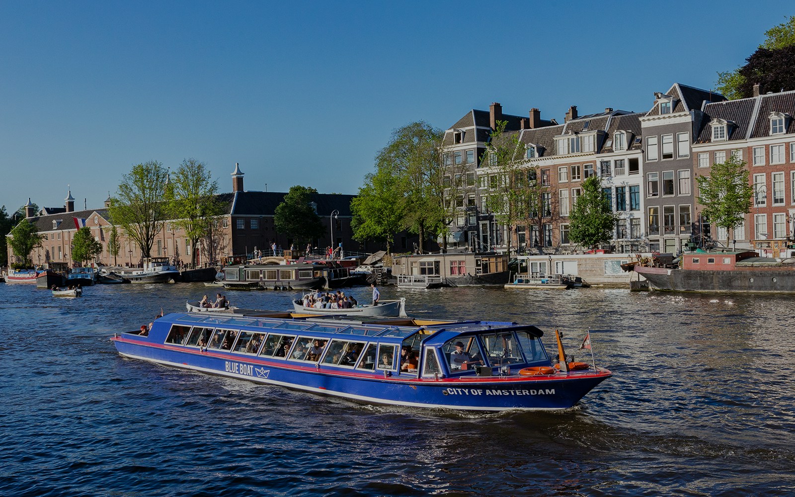 Amsterdam canal cruise boat passing historic buildings near Rembrandt House Museum.