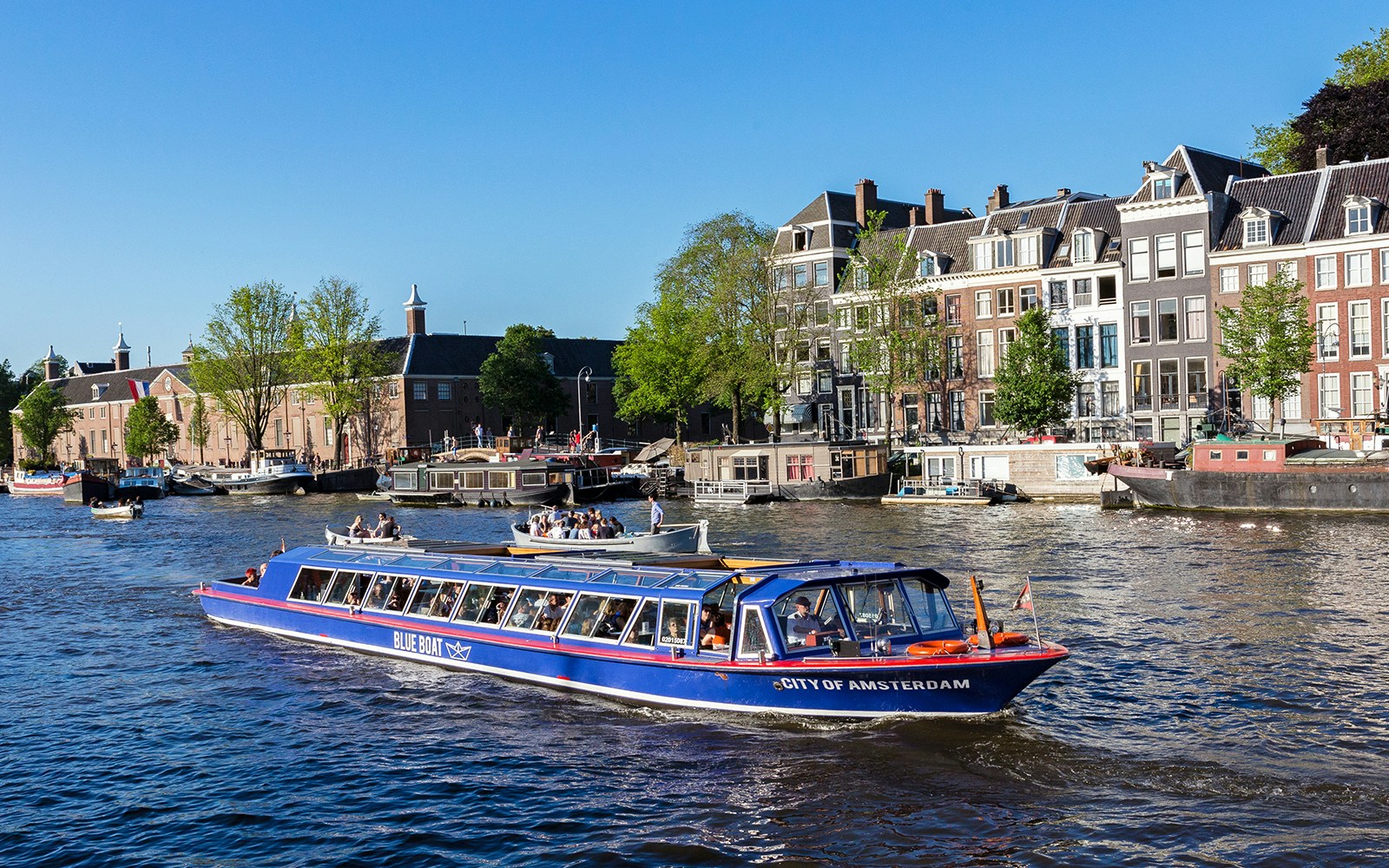 Amsterdam canal cruise boat passing historic buildings near Rembrandt House Museum.