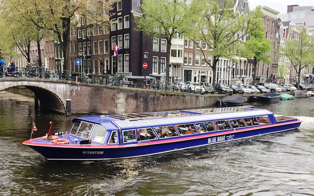 Amsterdam canal cruise boat passing historic buildings near Rembrandt House Museum.