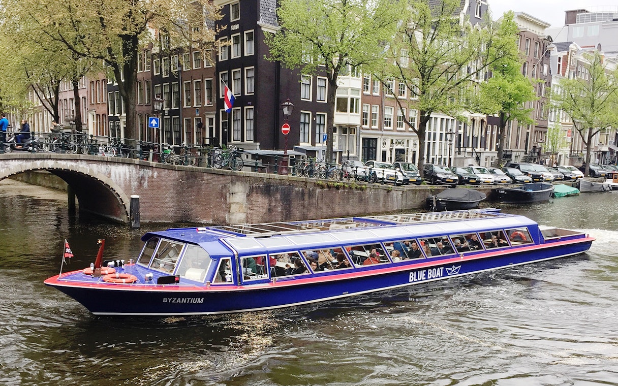 Amsterdam canal cruise boat passing historic buildings near Rembrandt House Museum.