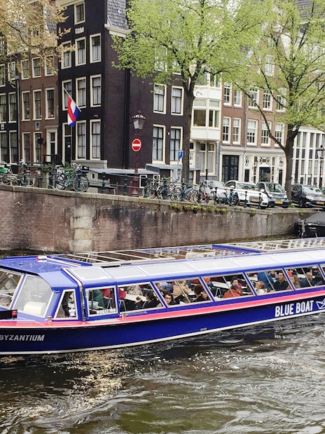 Amsterdam canal cruise boat passing historic buildings near Rembrandt House Museum.