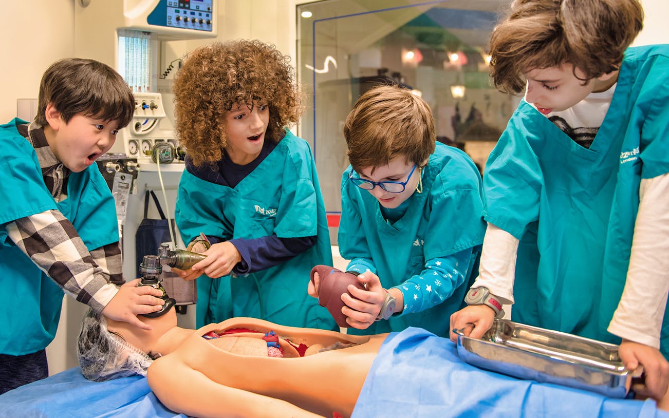 Children in medical uniforms performing a mock surgery at Kidzania.