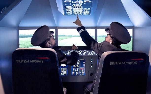 Children in pilot uniforms inside a flight simulator at Kidzania.