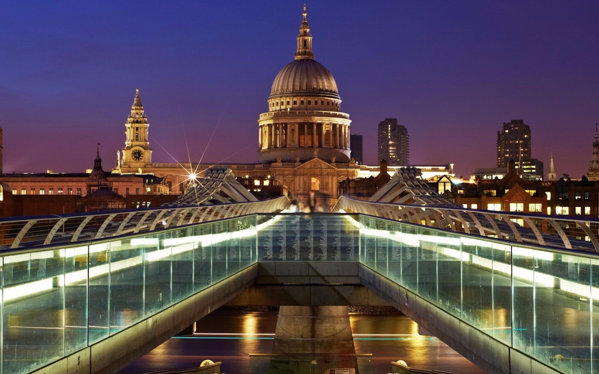 Millennium Bridge leading to St Paul's Cathedral in London at dusk.