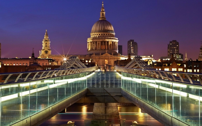 Millennium Bridge leading to St Paul's Cathedral in London at dusk.