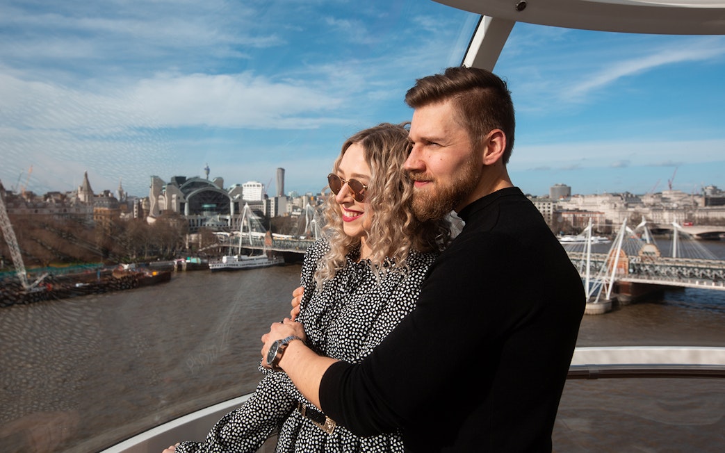 Couple enjoying view from London Eye capsule with cityscape and River Thames.