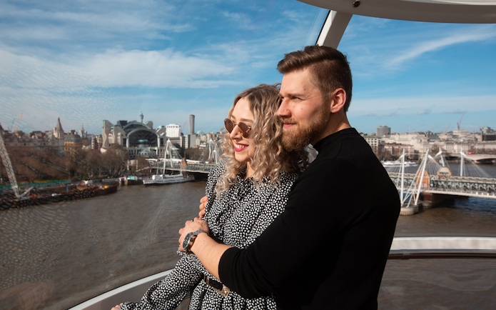 Couple enjoying view from London Eye capsule with cityscape and River Thames.