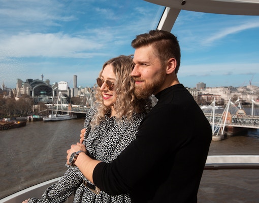 Couple enjoying view from London Eye capsule with cityscape and River Thames.