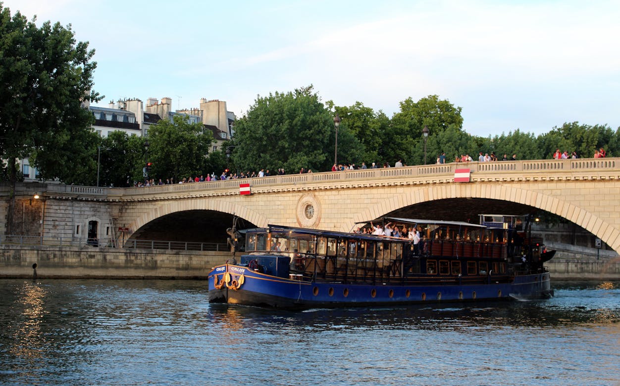 Seine River cruise boat passing under a bridge in Paris.