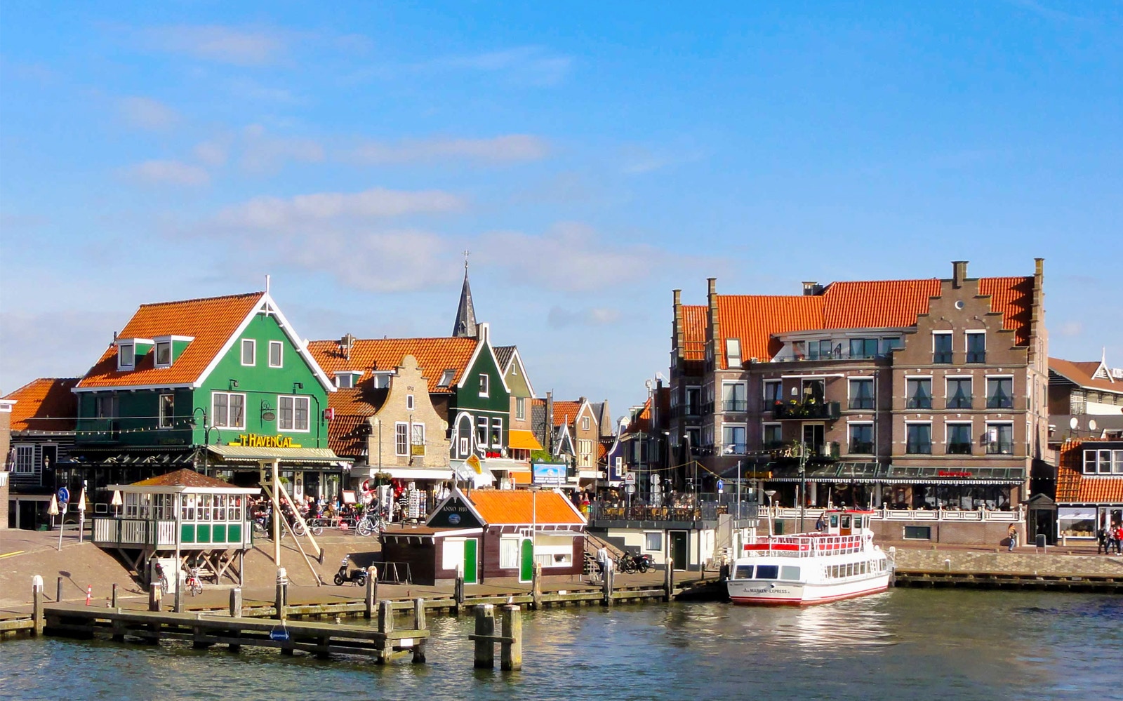 Volendam waterfront with colorful Dutch houses and a docked tour boat.