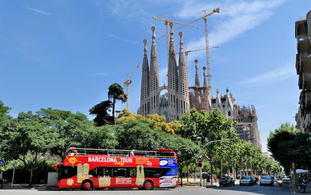 Barcelona tour bus in front of Sagrada Familia with cranes in the background.