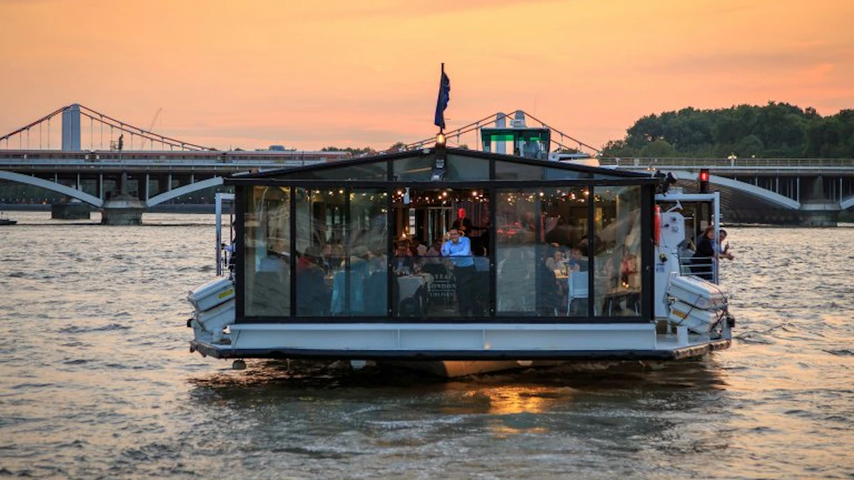 River cruise boat with dining area on the Thames at sunset, London.