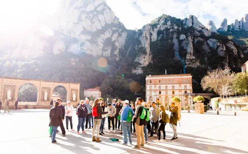 Group tour at Montserrat monastery with mountain backdrop, part of Montserrat, Sitges and Torres Wine Tour from Barcelona.
