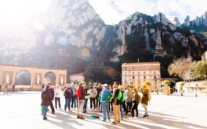 Group tour at Montserrat monastery with mountain backdrop, part of Montserrat, Sitges and Torres Wine Tour from Barcelona.