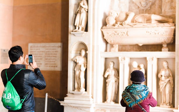 Tourists photographing sculptures at a historical site on the Montserrat, Sitges and Torres Wine Tour from Barcelona.