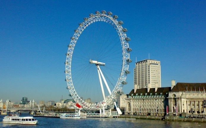 London Eye on the Thames River with nearby buildings.