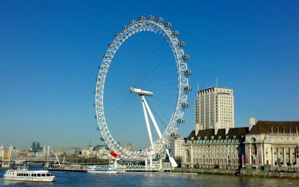 London Eye on the Thames River with nearby buildings.