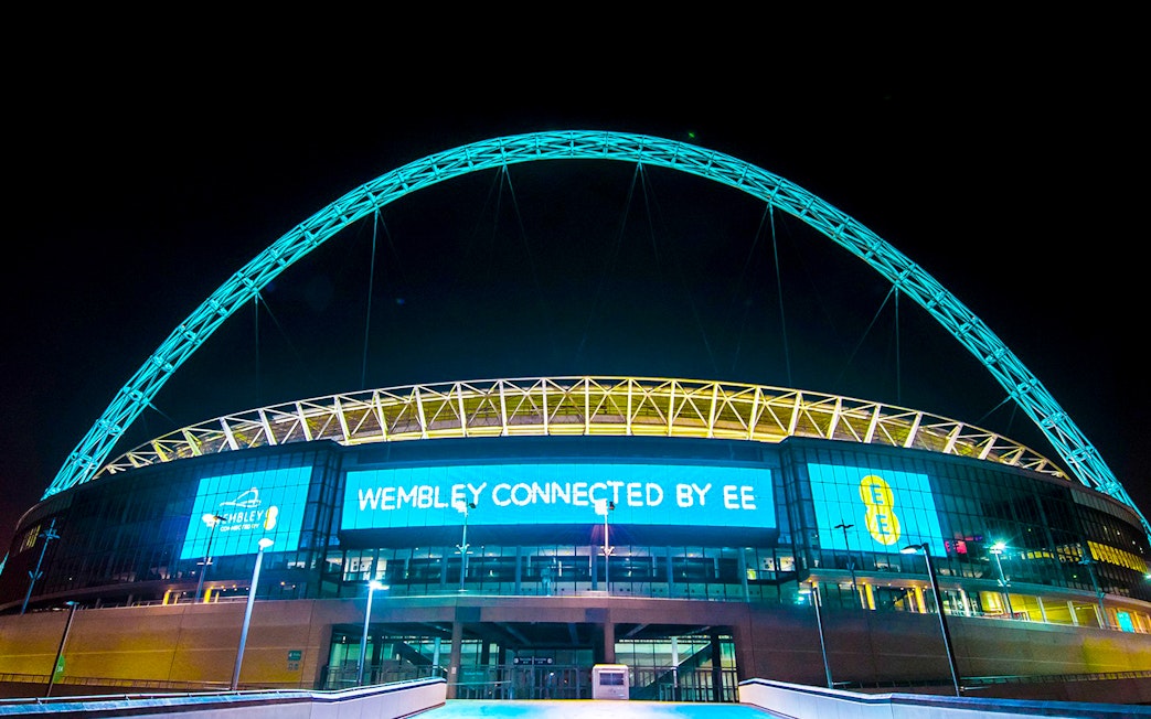 Wembley Stadium illuminated at night, showcasing the iconic arch in London.