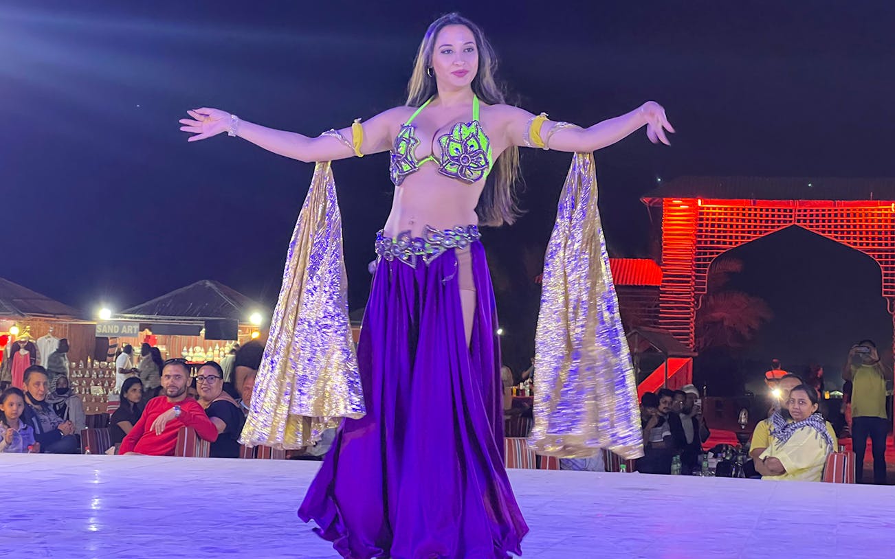 Dancer performing at VIP Majlis Seating Desert Safari with audience in background.