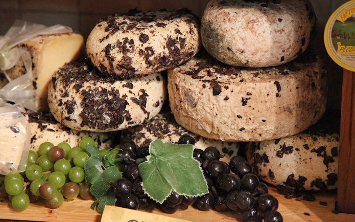 Cheese wheels with truffles and grapes, Tuscany tour highlight.