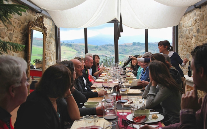 Group dining in a Tuscan restaurant with countryside views on a Rome day trip.