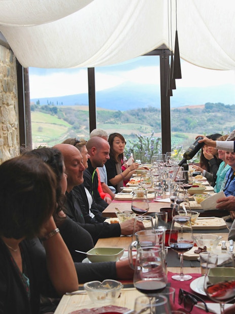Group dining in a Tuscan restaurant with countryside views on a Rome day trip.