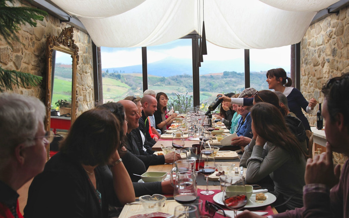 Group dining in a Tuscan restaurant with countryside views on a Rome day trip.