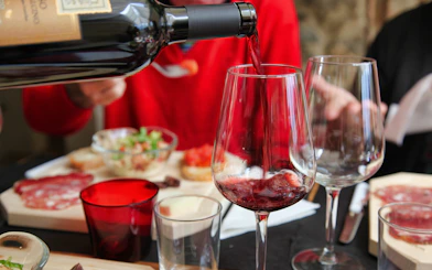 Pouring red wine at a Tuscan meal with charcuterie in Rome tour.