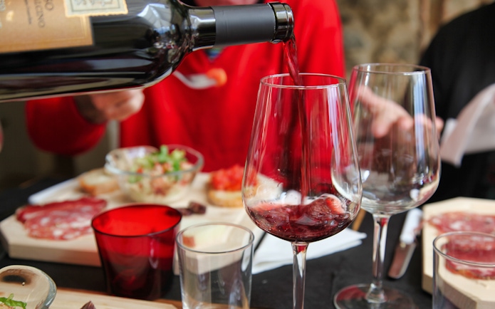 Pouring red wine at a Tuscan meal with charcuterie in Rome tour.