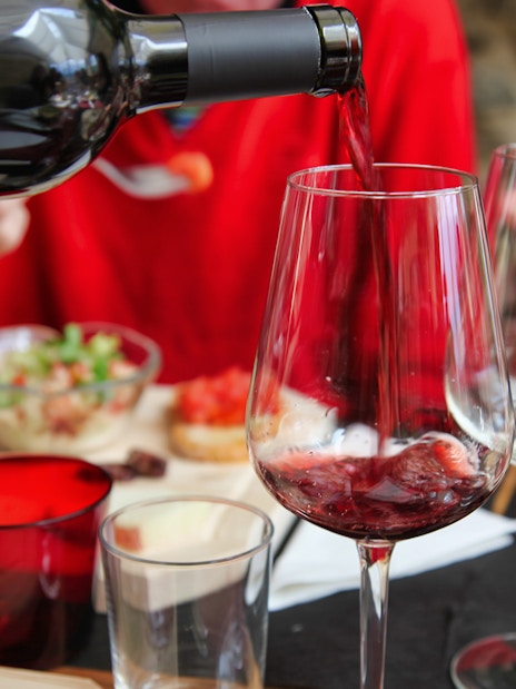 Pouring red wine at a Tuscan meal with charcuterie in Rome tour.