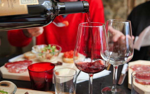 Pouring red wine at a Tuscan meal with charcuterie in Rome tour.