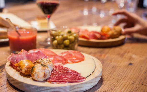 Tapas and wine selection on a wooden table during Montserrat walking tour.