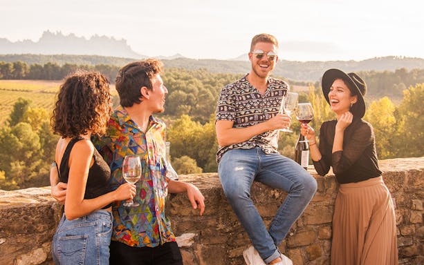 Group enjoying wine on Montserrat walking tour with scenic vineyard view.