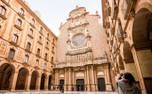 Montserrat monastery facade with tourists exploring the courtyard.
