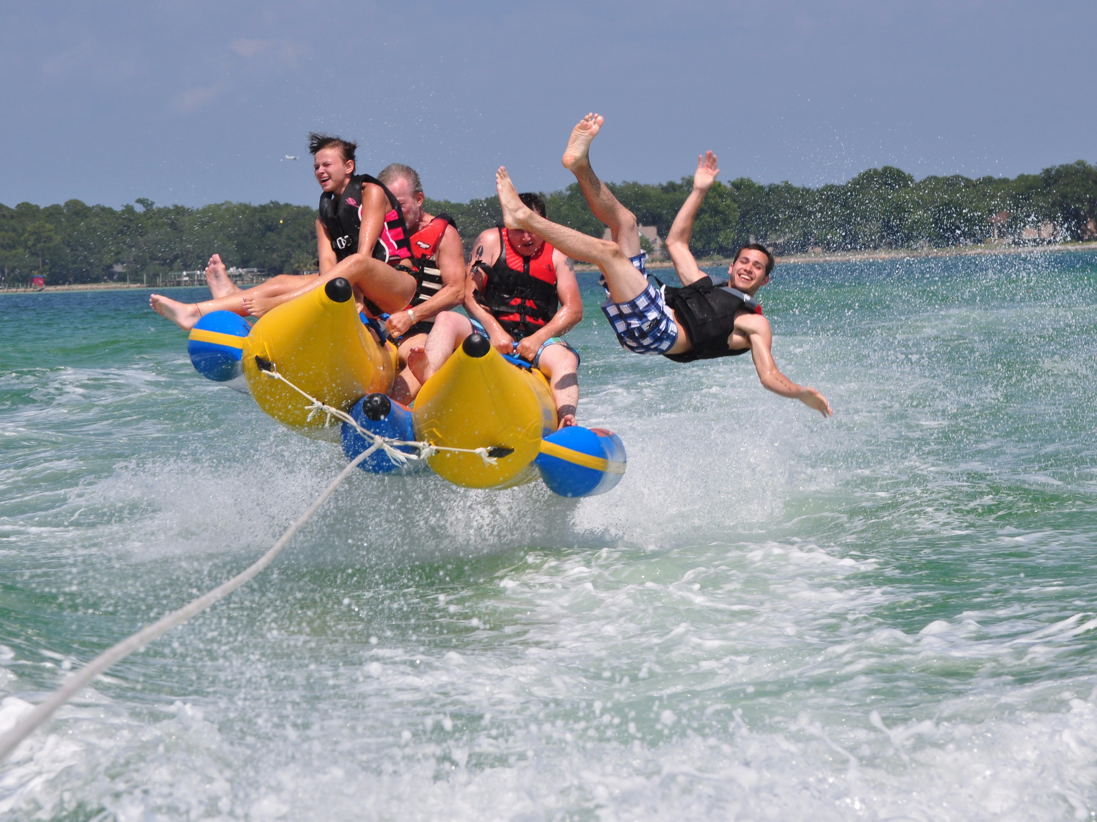 Group enjoying a banana boat ride on the ocean, with one person falling off.