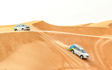 Desert safari vehicles driving over sand dunes during sunrise tour.