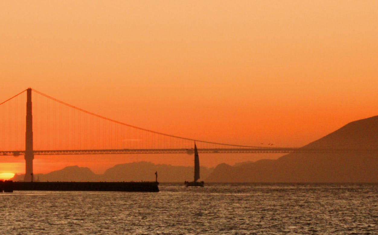 Golden Gate Bridge at sunset with sailboat, California cruise.