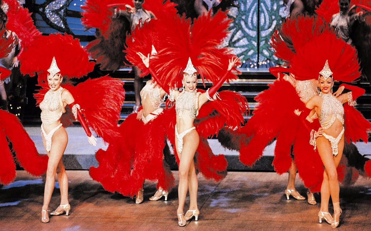 Dancers performing at Moulin Rouge in Paris with red feather costumes.