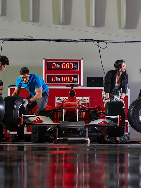 Ferrari World Abu Dhabi pit stop experience with visitors changing race car tires.