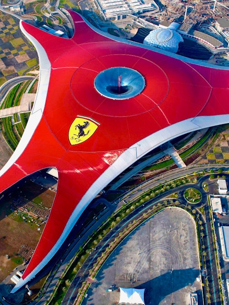 Aerial view of Ferrari World Abu Dhabi with its iconic red roof and surrounding landscape.