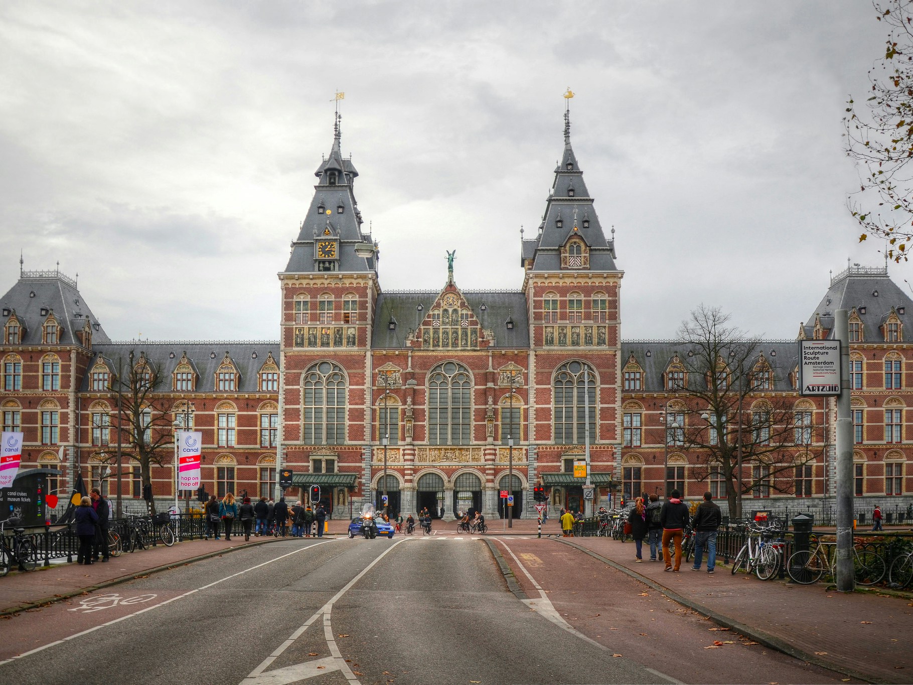 Rijksmuseum facade in Amsterdam with visitors and cyclists.