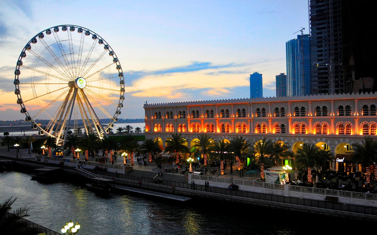 Ferris wheel and Al Qasba canal at sunset in Sharjah, UAE.