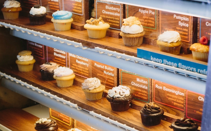 Cupcake display in New York bakery featuring various flavors for walking tour.